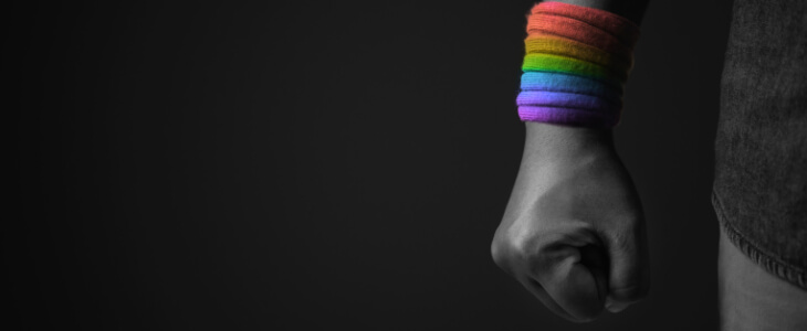 image of hand folded into a fist with pride color bracelets